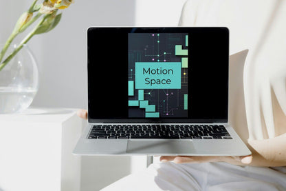 A silver laptop held by a person in a bright, modern room. The laptop screen displays a digital graphic with the text 'Drift Suite' in white on a teal background with abstract green and black geometric patterns.